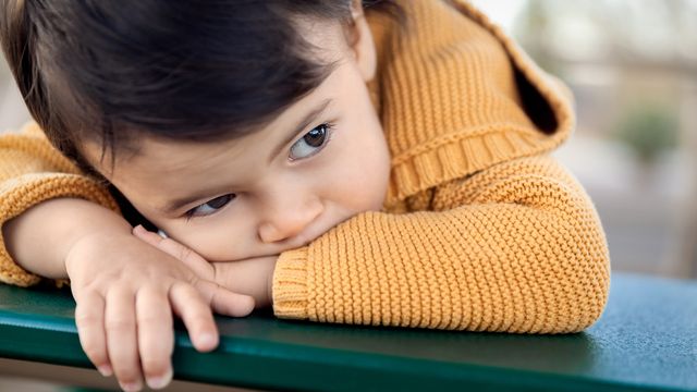 Ilustración de una niña con expresión triste sentada en el sofá